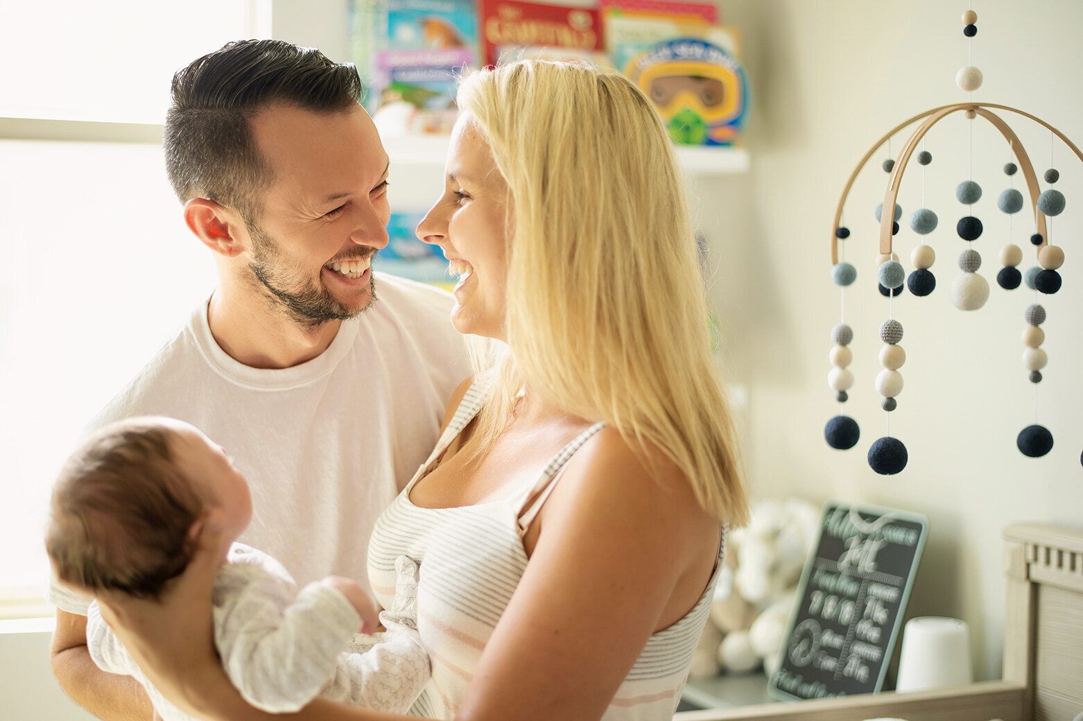 New parents laugh with their newborn during an in-home newborn session in Dallas