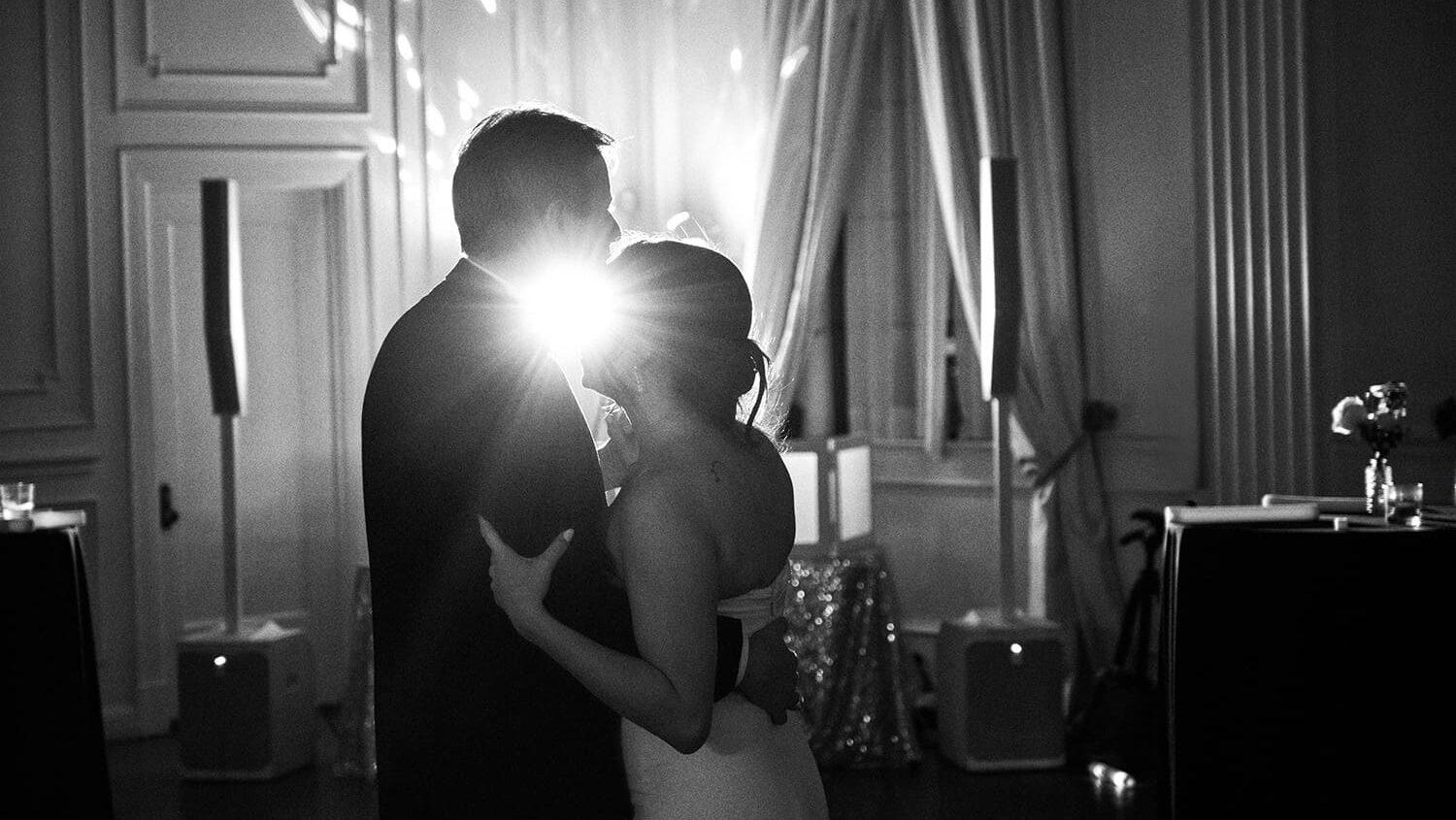 Black and white documentary photograph of a bride and groom sharing an intimate dance at a luxury Dallas wedding reception, illuminated by a cinematic backlight at The Mason Dallas.