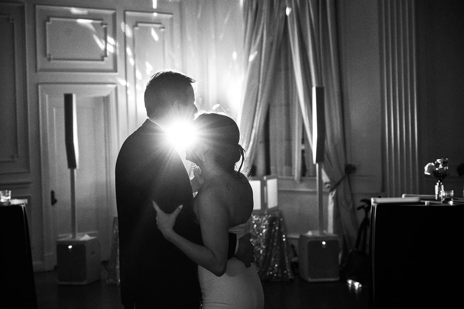Black and white documentary photograph of a bride and groom sharing an intimate dance at a luxury Dallas wedding reception, illuminated by a cinematic backlight at The Mason Dallas.