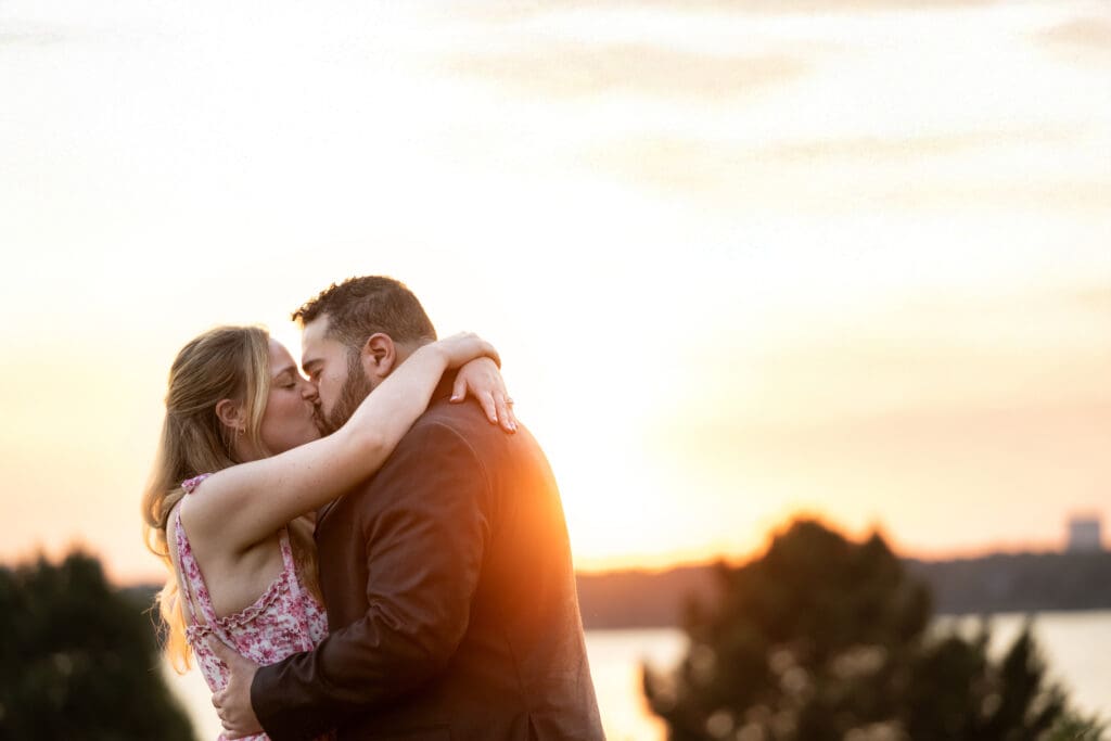 Newly engaged couple kiss at sunset, at White Rock Lake, in Dallas.