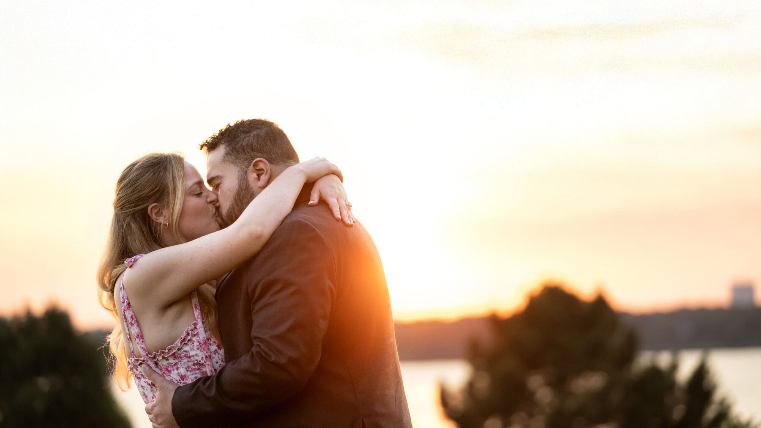 Newly engaged couple kiss at sunset, at White Rock Lake, in Dallas.
