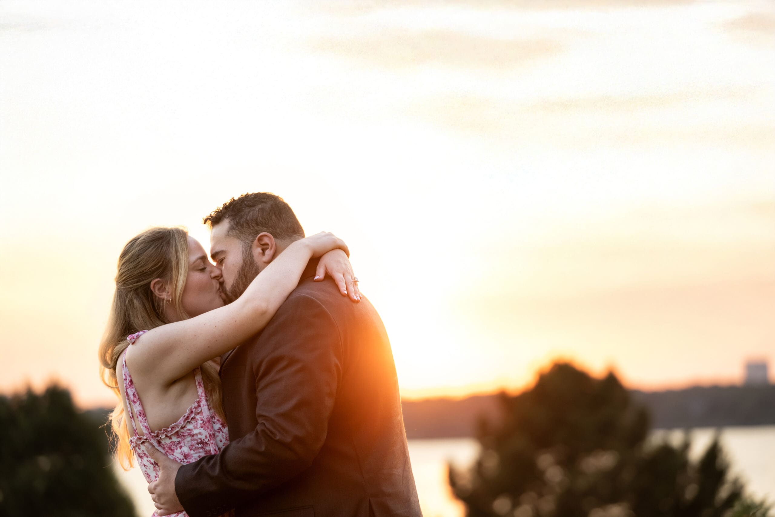 Newly engaged couple kiss at sunset, at White Rock Lake, in Dallas.