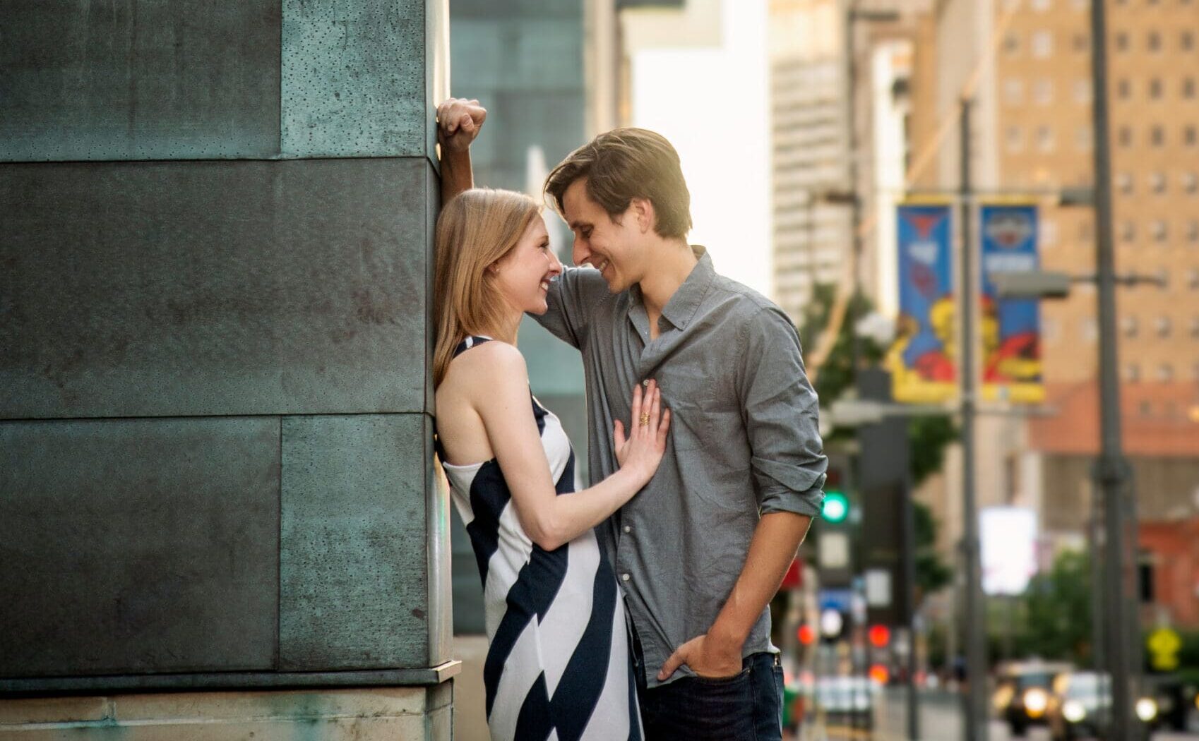 Couple sharing an intimate moment against the copper facade of Mercantile Place on Main with the Dallas skyline in the background