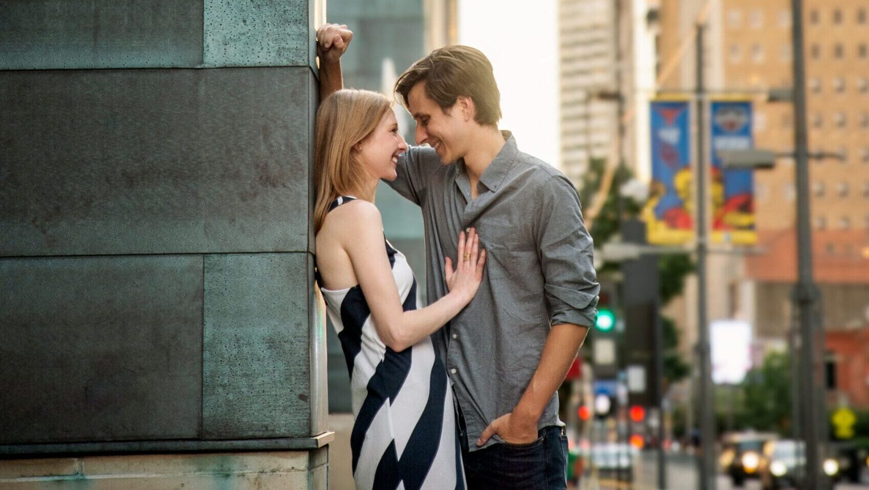 Couple sharing an intimate moment against the copper facade of Mercantile Place on Main with the Dallas skyline in the background