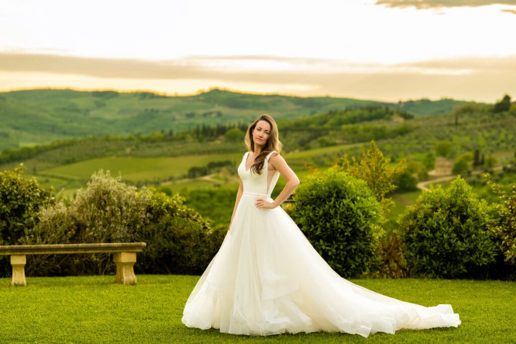 Bride in a wedding dress taking a quiet moment, looking out over a Tuscan valley at sunset.