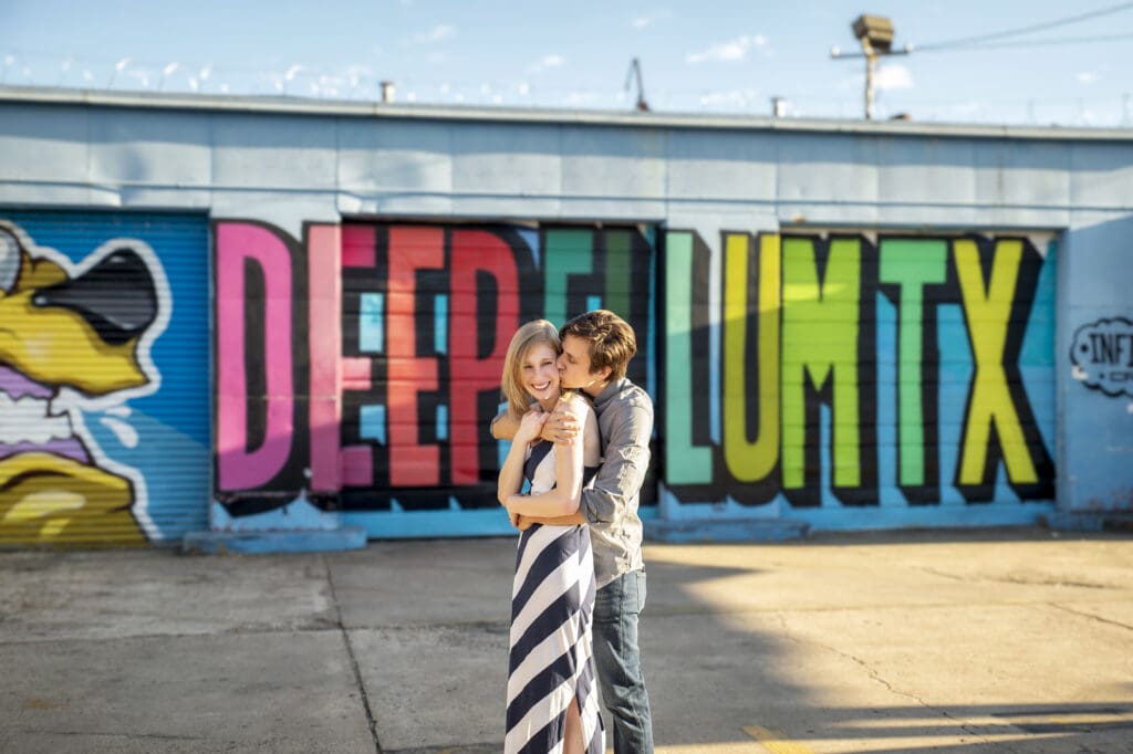 Couple standing in front of the Deep Ellum TX colorful mural during an engagement session in Dallas
