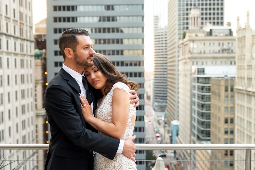 Modern couple embracing on a high-rise balcony with the Dallas city skyline in the background.