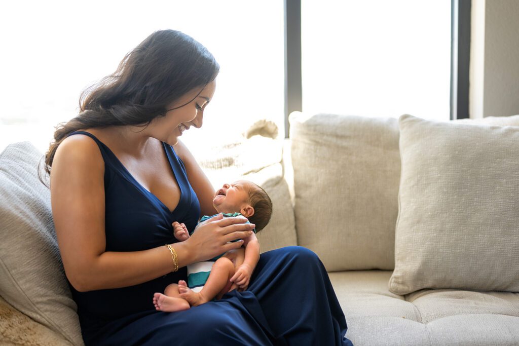 Natural light lifestyle newborn photography of a mother and father smiling down at their baby during a Dallas in-home session.